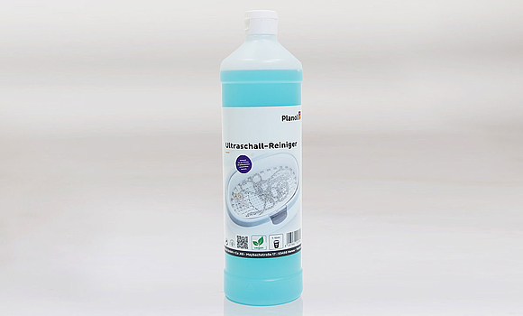 Blaufarbener Ultraschallreiniger in weißer Flasche mit Etikett vor grauem Hintergrund